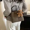 Bolso de hombro estilo coreano para el otoño de 2026, con un pequeño charm de oso, un bolso tipo cubo nuevo y elegante para mujer, simple y versátil