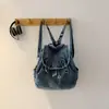 Mochila de mezclilla de moda estilo callejero con solapa y cierre de cordón, una bolsa ligera y versátil adecuada para que los estudiantes la usen para la escuela o como bolso de mano informal.