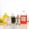 Botella de bebida de jugo de alto valor al por mayor de fábrica, botella de vidrio de vino, botella de vidrio transparente de capacidad múltiple plana con tapa