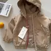 Jaqueta com Capuz Infantil 2026 Primavera e Outono Novo Estilo Top para Meninos Cor Sólida Marca Tendência Corta-vento com Cordão para Bebê Estilo Fashion para Meninas