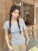 Camiseta Branca de Ombro Inclinado com Estampa de Letras Retrô Americana para Mulheres Verão Nicho Look Emagrecedor Chique Top Curto Ombro a Ombro