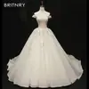Novo Vestido de Noiva 2026 Cor Champanhe Off-Shoulder com Renda e Pedrarias, Alta Costura Feito Sob Medida com Cauda Longa e Saia Volumosa Estilo Corte