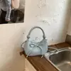 Bolso de media luna de nicho estilo coreano, bolso de mano nuevo de un solo color con lazo, bolso cruzado casual y moderno para mujer al por mayor