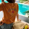 Chegada Nova Verão 2026 Camiseta com Estampa de Letras Gola Redonda Ombro Normal Manga Curta para Mulheres Emagrecedora Casual Versátil Top Chique