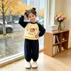 Novo conjunto de menina estilo doce: um conjunto de duas peças com uma blusa de moletom color block, com babados e gola redonda, e calças compridas até o tornozelo com mangas compridas.