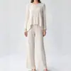 Ropa de mujer plisada estilo Miyake: Top de cuello redondo, de un solo botón, con bajo asimétrico, combinado con pantalones de pierna ancha que estilizan para un look elegante