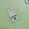 Etiquetas de Talla en Stock al por Mayor Planas de Doble Tejido Etiquetas de Origen con Letras Entrega Directa de Fábrica Accesorios Universales para Ropa