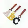 Acessórios de couro feitos sob medida para bolsas, incluindo chaveiros de couro PU, pingentes personalizados para bolsas e pingentes de couro acolchoados em formatos únicos e em forma de letras.