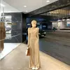Roupa de primavera cedo: um conjunto de duas peças apresentando um top pequeno, ombro a ombro, de manga longa e com efeito rejuvenescedor, e calças casuais de perna larga