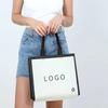 Bolsa de tela no tejida de borde negro transfronterizo, película engrosada, bolso de mano termoprensado, bolsa de compras, fábrica de tienda de ropa en stock al por mayor