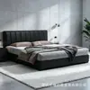 Cama estilo italiano em couro preto com estofamento segmentado em listras verticais, apresentando acabamento em couro Nappa, bordas niveladas e uma estrutura de piso, adequada para o quarto principal ou secundário