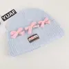 Gorro de punto de estilo coreano inspirado en la dopamina con un lazo, diseñado para mujeres, que proporciona calor y protección para los oídos en otoño e invierno, y favorece el rostro; un sombrero pequeño y elegante para estudiantes