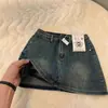 Mini saia jeans de cintura alta estilo retrô de Hong Kong para mulheres, novo modelo 2026, anti-exposição, corte A, justa ao quadril, emagrecedora, versátil, moderna, cor sólida