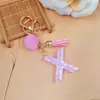 Llavero de letra inglesa rosa, un accesorio lindo y moderno con un pompón esponjoso y un borla, perfecto para proyectos de bricolaje y como charm para bolso para mujeres