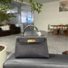 Mini bolso Kelly cosido a mano con hilo encerado de patrón de lagarto, forro de piel de vacuno de plena flor, detalles tachonados a mano de piel de oveja y herrajes de acero completo
