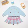Conjunto de Suéter de Tricô para Meninas 2026 Outono/Inverno Novo Estilo Coreano Cardigã Bordado Infantil Conjunto de Duas Peças com Saia Xadrez Transfronteiriço