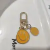 Llavero de cara sonriente de color aleación con goteo transfronterizo de comercio electrónico, accesorios de colgante para bolso con expresión irregular chapado en oro