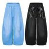Calça de moletom azul claro lavada, modelagem solta e pernas largas, com fileira vertical de rebites e bordado de estrela de cinco pontas nas pernas, fechamento por cordão na barra, para homens e mulheres