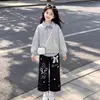 Elegante y a la moda conjunto de dos piezas para niñas para primavera y otoño: un top a rayas con un diseño de cuello único, combinado con pantalones casuales con delicados detalles de encaje - un conjunto de dos piezas moderno