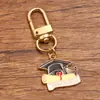 Varios accesorios de joyería de aleación personalizados transfronterizos europeos y americanos para la temporada de graduación, incluyendo encantadores colgantes de birrete, flores y exámenes.