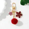 Nuevo llavero colgante de flor de pompón de flor de cerezo estilo japonés personalizado, aleación con goteo de aceite, decoración pequeña para funda de auriculares estilo Chanel