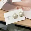 Moda de nicho pendientes elegantes de alta calidad pendientes de lujo ligero versátiles pendientes al por mayor de aguja de plata pendientes de círculo retorcido de perlas para mujer