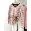 Foto real de uma camiseta feminina listrada de manga comprida, suave e que valoriza a silhueta! Estilo coreano de primavera, casual, solta, modeladora, com gola redonda, para usar como base