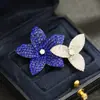 Elegante y sofisticado accesorio de broche floral con diseño intrincado, incrustación sin bordes de piedras de imitación rubí, y flores dobles unidas entre sí.