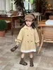 Chegada Nova Outono 2026 Estilo Coreano Roupas Infantis Casaco Trench Coat Feminino de Comprimento Médio com Acabamento em Renda e Laço nas Costas em Estilo Britânico