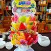 Paletas y Caramelos Duros en Varias Formas de Frutas para que los Niños Compartan Dulces y Den a sus Amigos Regalos Navideños. Puestos en la Puerta de la Escuela