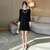Elegante vestido preto de veludo estilo francês com detalhes de pérolas e gola contrastante, perfeito para outono e inverno, criando um visual chique e sofisticado.