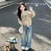 Conjunto de suéter para meninas, nova coleção outono 2026, apresentando um suéter de tricô com urso de desenho animado e calça jeans de perna larga, um conjunto de duas peças em um estilo coreano moderno
