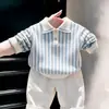 Ropa infantil coreana 2026 otoño nuevo suéter de punto con cuello polo a rayas azules conjunto de pantalones casuales blancos para niños