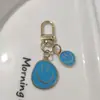 Llavero de cara sonriente de color aleación con goteo transfronterizo de comercio electrónico, accesorios de colgante para bolso con expresión irregular chapado en oro