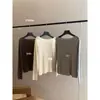 Dela, um top de malha simples e elegante de manga longa com design de ombro inclinado, perfeito para o início do outono de 2026, exalando uma vibe pura e sedutora.