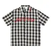 Camisa Original Retro a Cuadros Blanco y Negro Desgastada de Manga Corta para Hombres y Mujeres, Top Juvenil Holgado Estilo Urbano con Letras Rosas