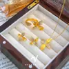 Set de Lirio Dorado Arena Estilo de Lujo Ligero Gama Alta Collar Anillo Pendientes Flor de Cuatro Hojas Punto de Hada Diamante para Mujer Venta al por Mayor