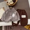 Novo conjunto estiloso de outono e primavera para meninos: camisa de algodão xadrez, colete de tricô e calça - um conjunto de três peças em estilo preppy