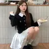 Look préppy para o início do outono: um conjunto de duas peças composto por um suéter cardigã falso de duas peças com blocos de cor e uma meia-saia plissada