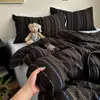 Juego de cuatro piezas de algodón acolchado con estampado de rayas minimalista con sábana bajera y funda de edredón de doble cara