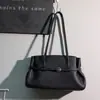 Bolso de bowling de cuero de grano superior estilo 2026 para mujer, con un sofisticado diseño de cuero suave, adecuado como bolso de mano, bolso de hombro o bolso tote para el trabajo diario.