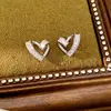 Pendientes de aguja plateada con diseño de corazón hueco incrustado con circonita, exquisitos y elegantes, versátiles para el uso diario, lujo ligero y sensación de alta gama, pendientes al por mayor