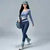 Conjunto de fitness Pilates sin costuras y apto para la piel para mujer, con un top de manga larga de cuello redondo y bloques de color, y unos leggings de cintura alta con diseño cruzado que levantan y moldean las caderas