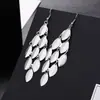 Los pendientes transfronterizos europeos y americanos de moda presentan una variedad de elementos populares largos con borlas exageradas de metal de moda, pendientes con gancho para la oreja.