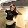 Camiseta de Manga Curta com Estampa de Letras 2025 para Mulheres no Verão Americana Sexy Slim Fit Mostrando o Umbigo Curta Preta Ombro Direito Top Tendência