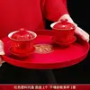 Um conjunto de xícaras de chá de casamento, incluindo um par de tigelas de chá e pauzinhos vermelhos e festivos, perfeito para servir chá durante a cerimônia de casamento.