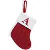 Calcetines navideños rojos exquisitos con letras, bolsas de dulces y adornos para colgar en el árbol de Navidad.
