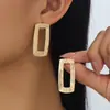 Um par de brincos femininos simples, quadrados, texturizados e vazados, modernos para o uso diário.
