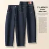 Jeans feminino azul escuro de cintura alta, corte reto (estilo cenoura), modelagem solta, com barra dobrada, comprimento cropped e efeito emagrecedor, modelo 2026