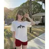 Camiseta Feminina de Manga Curta IA Verão 2026 Novo Estilo Design de Estampa de Filhote Senso de Design Puro Desejo Ombro a Ombro Top Assimétrico no Ombro